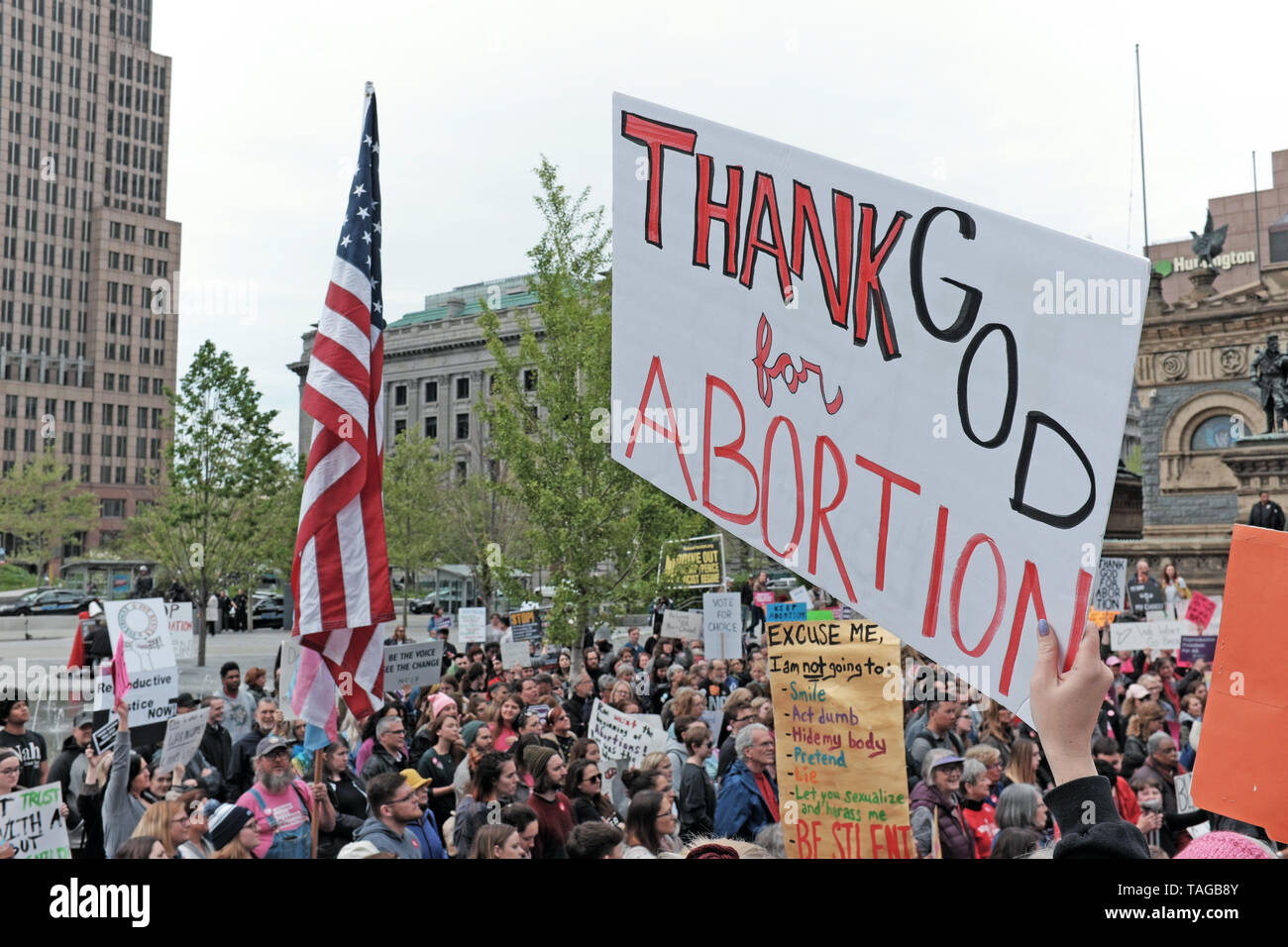 'Thank God for Abortion' is held up while a US flag is flown nearby during the 2019 Women's Rights Rally in Public Square of Cleveland, Ohio, USA. Stock Photo