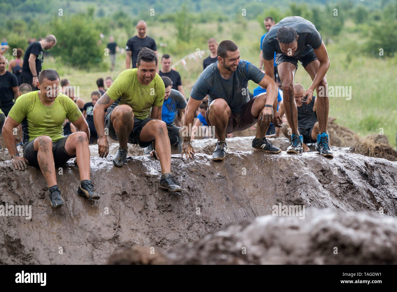 SOFIA, BULGARIA - JULY 7 2018: a team of men jumping in a mud poll to overcome the obstacle course in a strength mud race Stock Photo