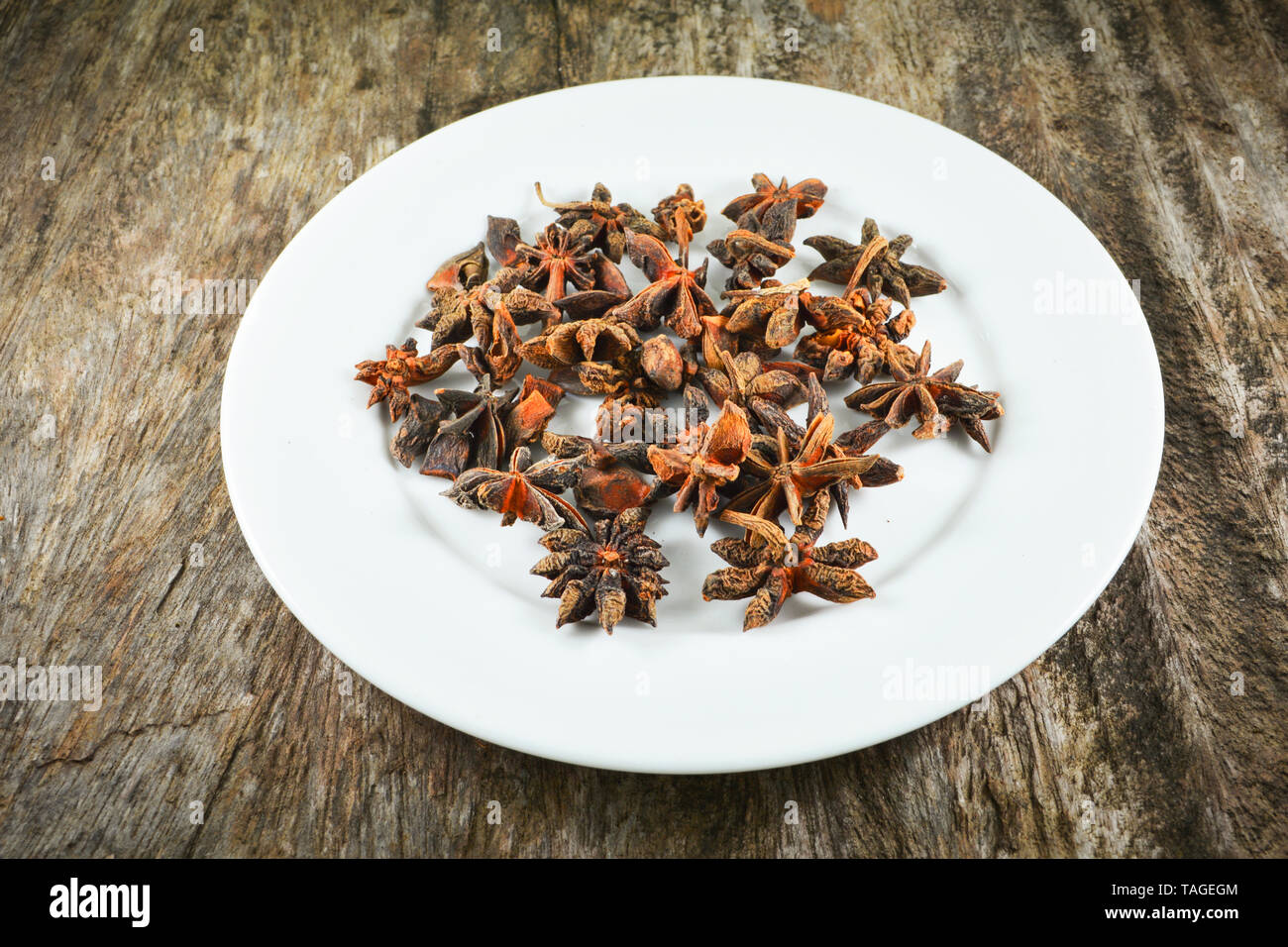 Chinese star anise spice fruit on white plate on wood background Other names star aniseed