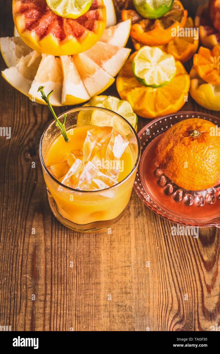 Fresh squeezed citrus juice in glass with ice cubes on table with ingredients:  orange, lemon, grapefruit, mandarin, lime. Healthy lifestyle . Vitamin Stock Photo