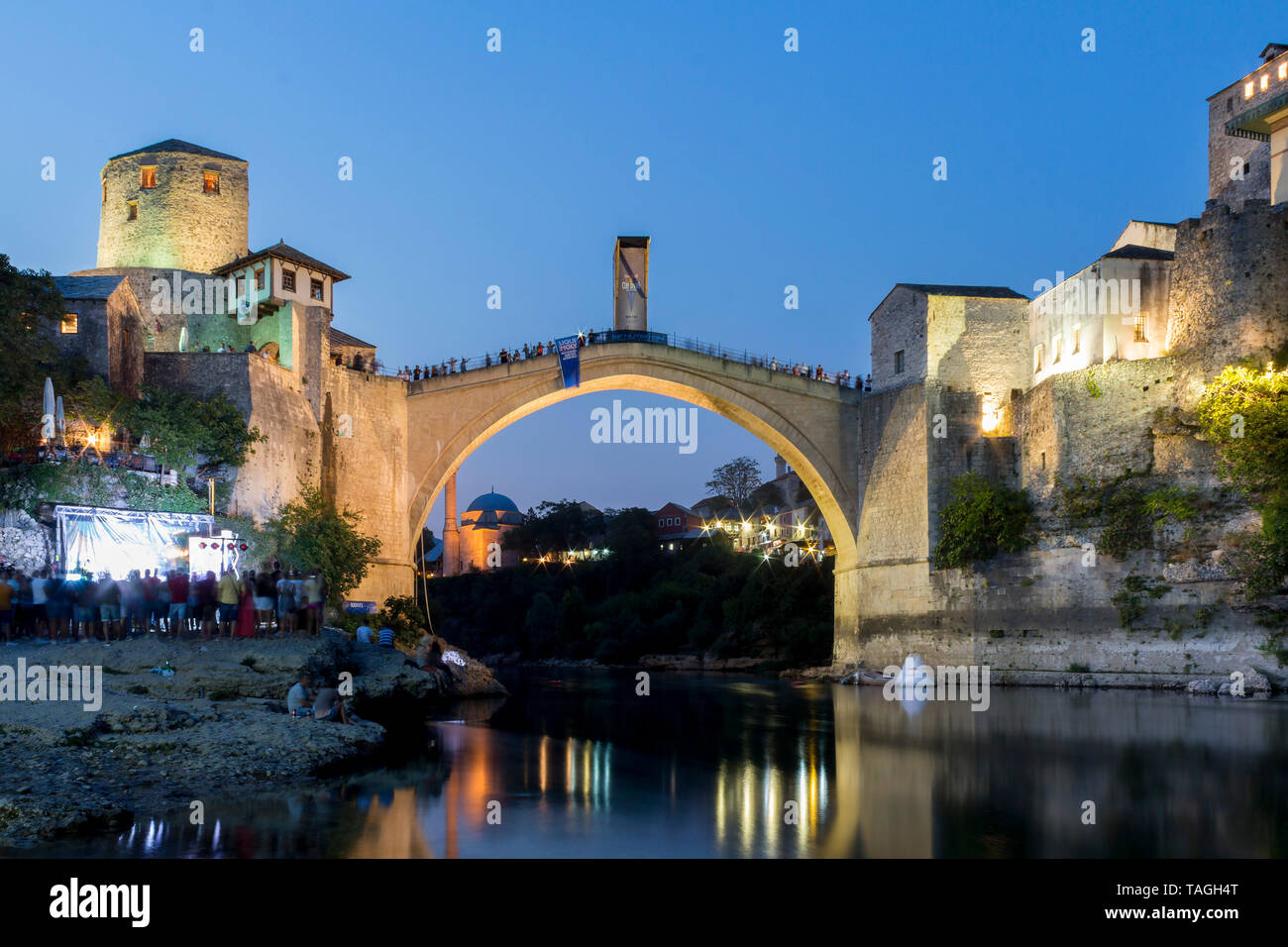 MOSTAR, BOSNIA AND HERZEGOVINA - AUGUST 13, 2015: Dusk photo of Tourist and locals walking near Old bridge in Mostar while there are preparation for R Stock Photo
