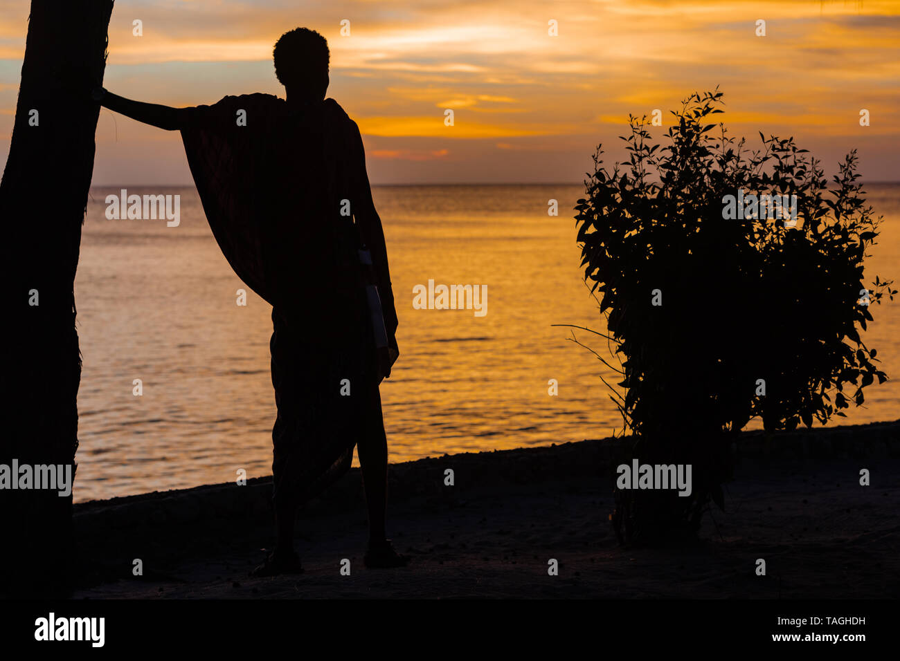 Masai man looking at sunset over the sea at Kizimkazi in Unguja aka Zanzibar Island Tanzania East Africa Stock Photo