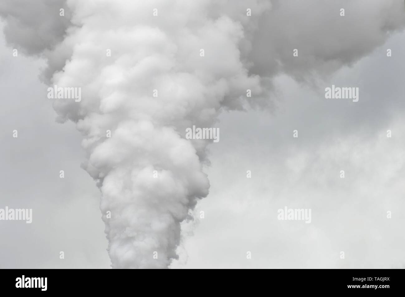 impressing cloud of smoke joining the rain clouds in the sky Stock Photo