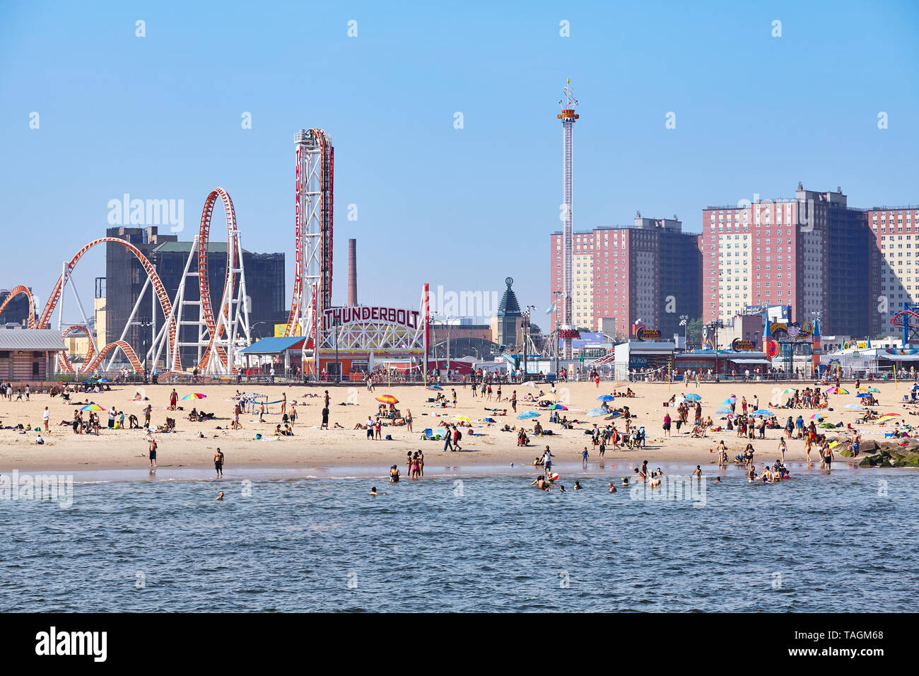 New York, USA - July 02, 2018: Crowded Coney Island beach and amusement parks seen from the pier on a sunny day. Stock Photo
