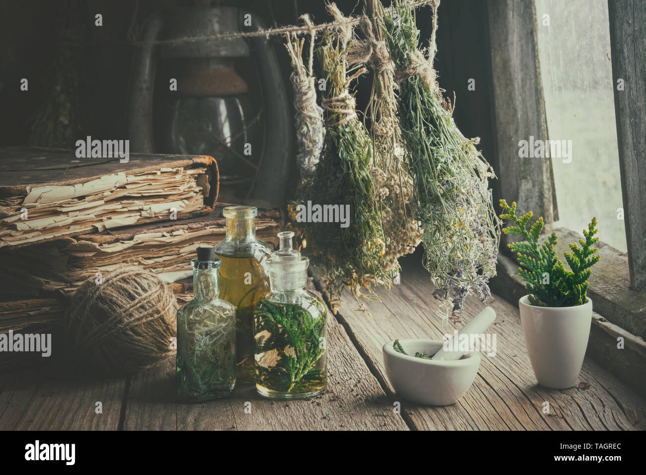 Infusion bottles, old books, mortar and hanging bunches of dry medicinal herbs. Herbal medicine. Retro styled. Stock Photo