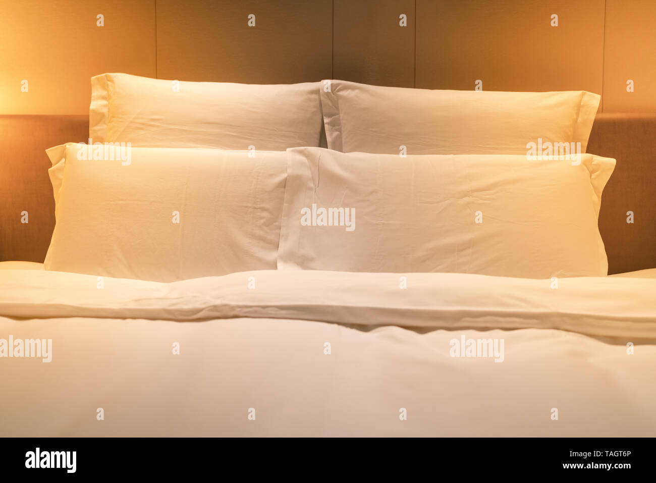 White sheets king size bed with double pillows and warm light Stock Photo