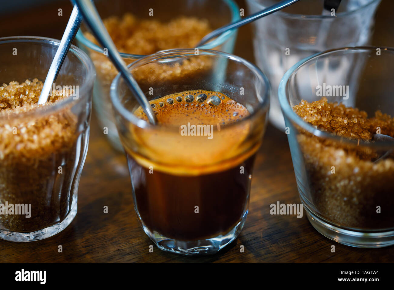 foamy espresso coffee in glass cup with metal spoon and sugar Stock