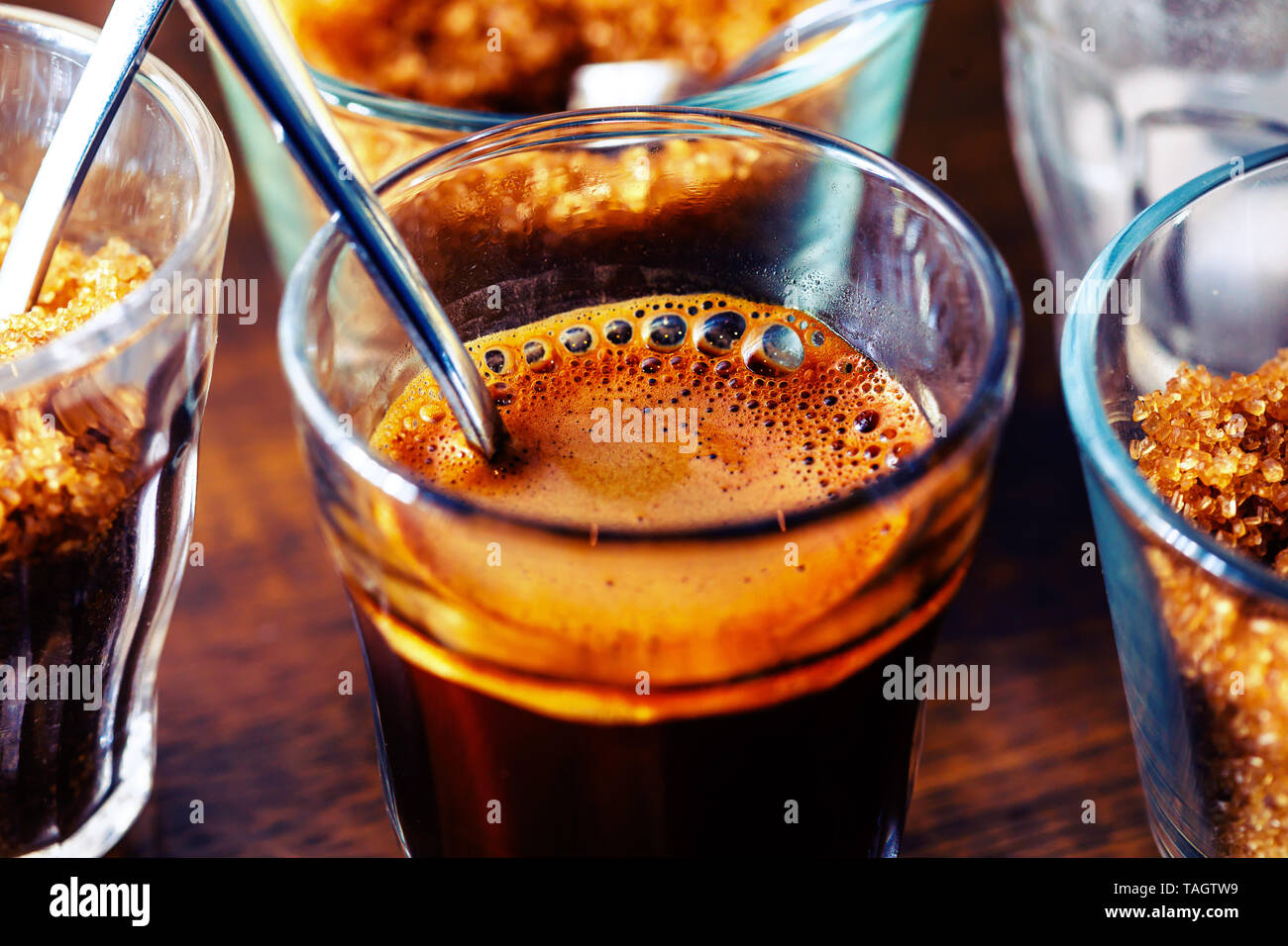 foamy espresso coffee in glass cup with metal spoon and sugar Stock
