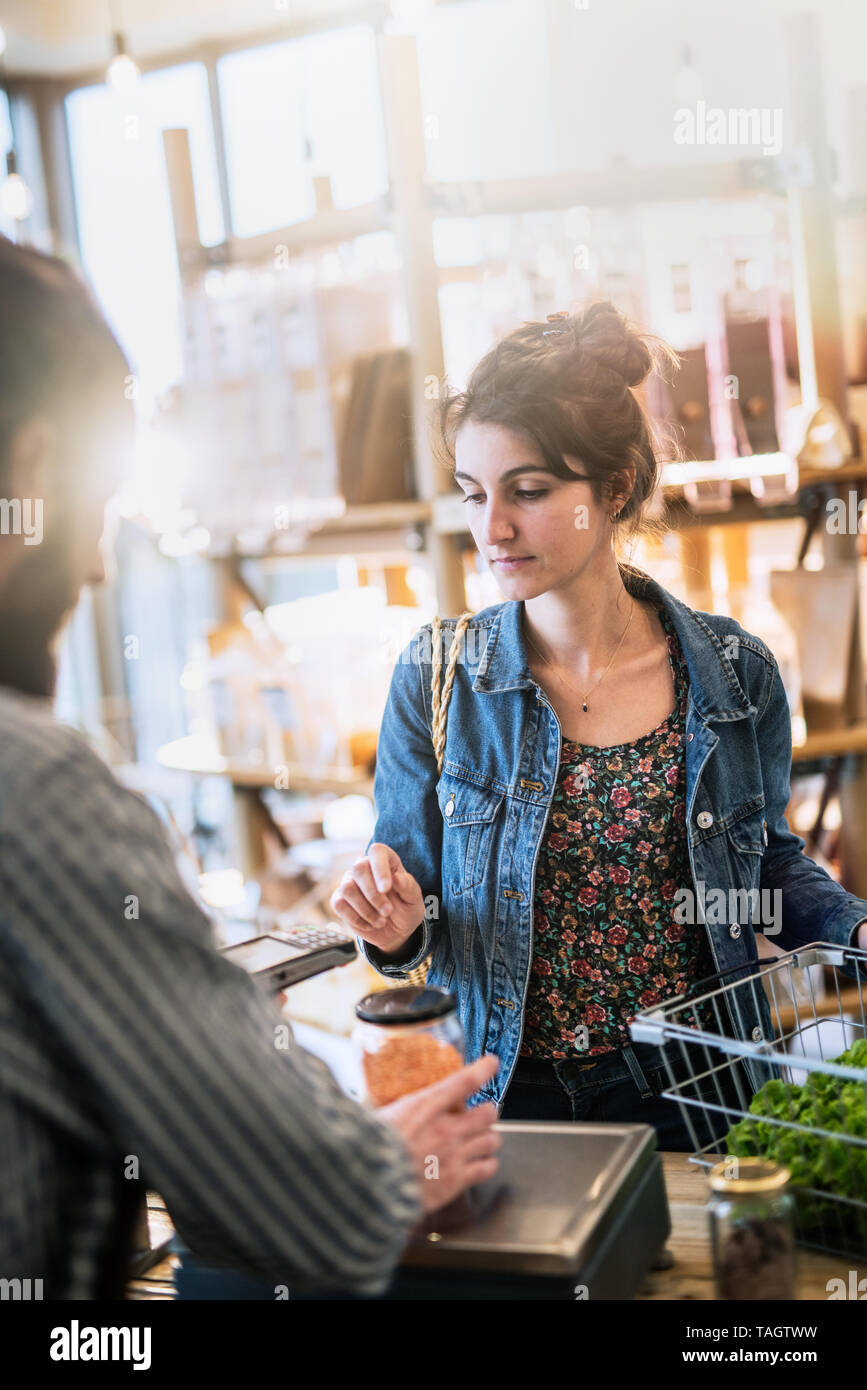 In a grocery store, a young woman at the cash register  Stock Photo