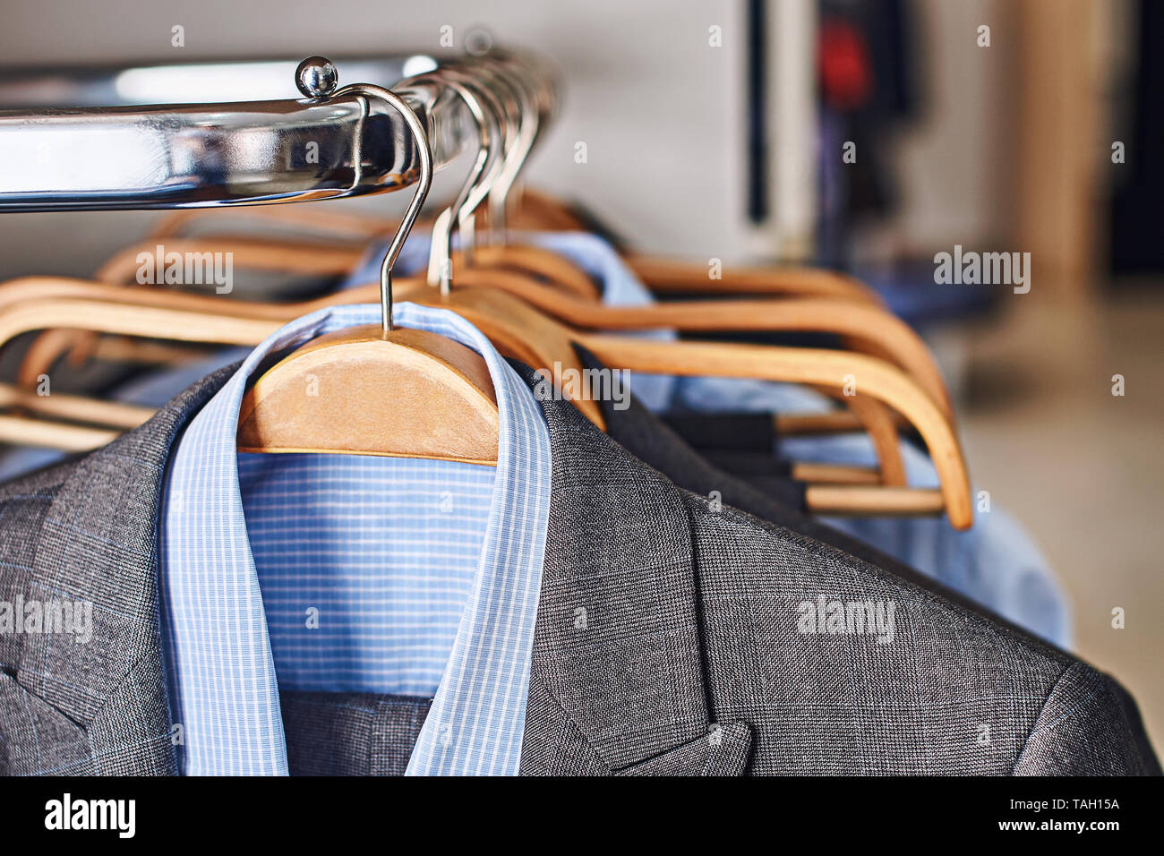 Mens suits and formal shirts on wooden hangers in a clothes store Stock Photo
