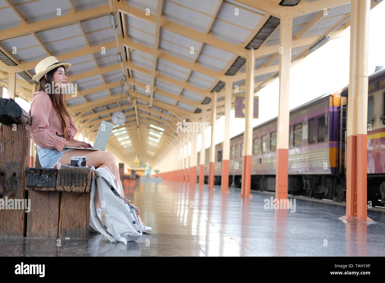 young woman traveler using computer at train station. Travel journey ...
