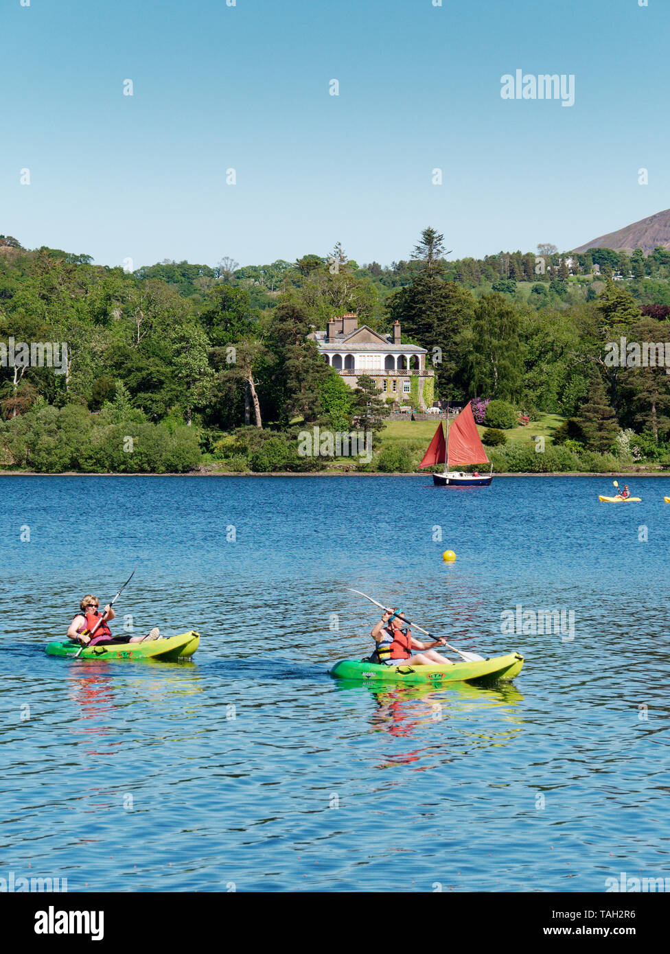 A couple having fun in the sun with their canoes on Derwent Water Lake in the English Lake District Stock Photo