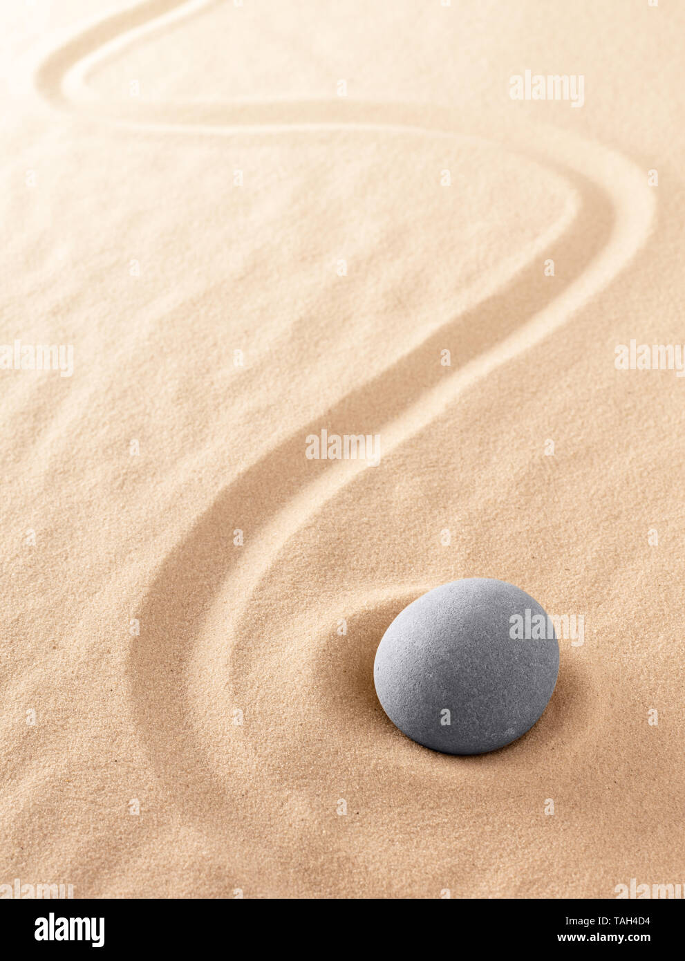 Zen meditation stone to focus and concentrate for a quiet peace of mind. Spiritual raked sand background texture. Concept for harmony purity and spiri Stock Photo