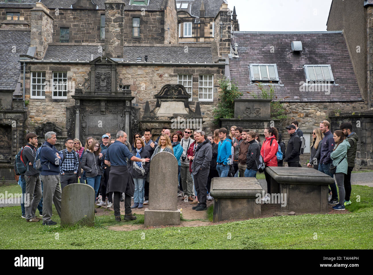Tourists on a walking tour of Edinburgh visit the grave of John Gray, the master of Greyfriars Bobby, in Greyfriars Kirkyard. Stock Photo