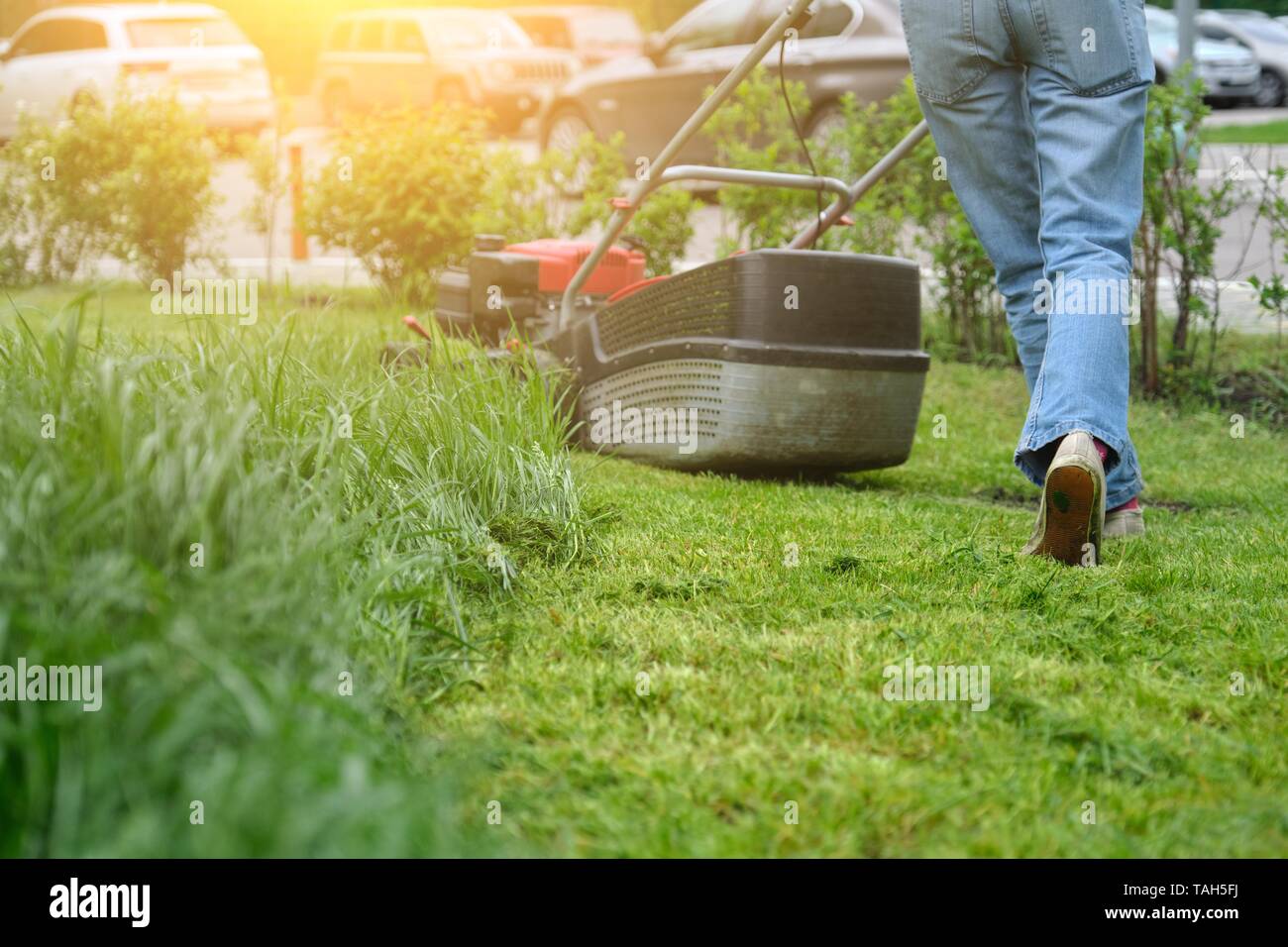 gardener-woman-legs-mowing-grass-with-lawnmower-city-courtyard-of-an