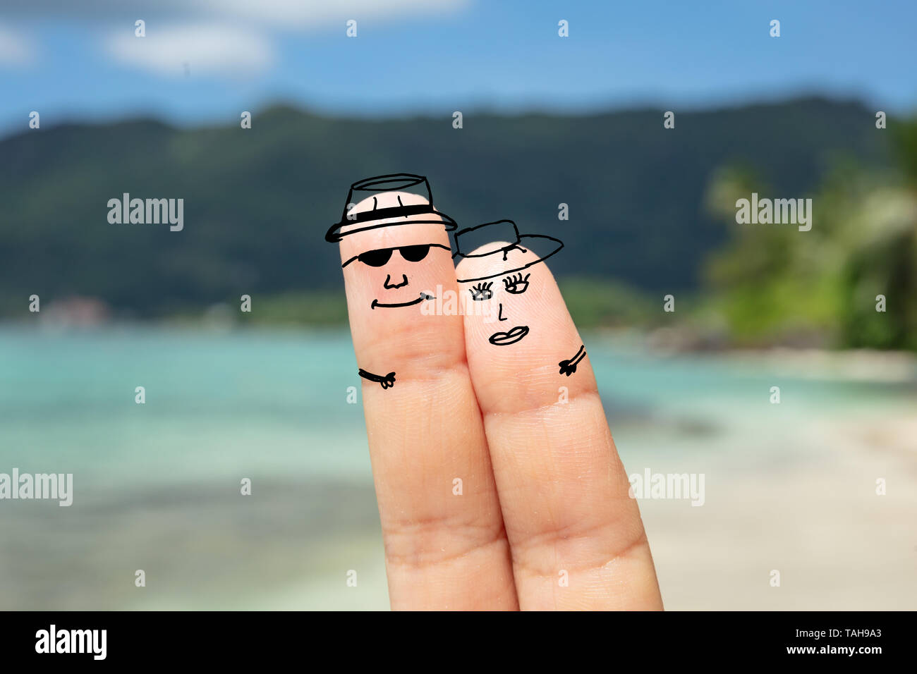 Close-up Of Happy Couple Faces On Human Finger Against Blurred Beach Stock Photo