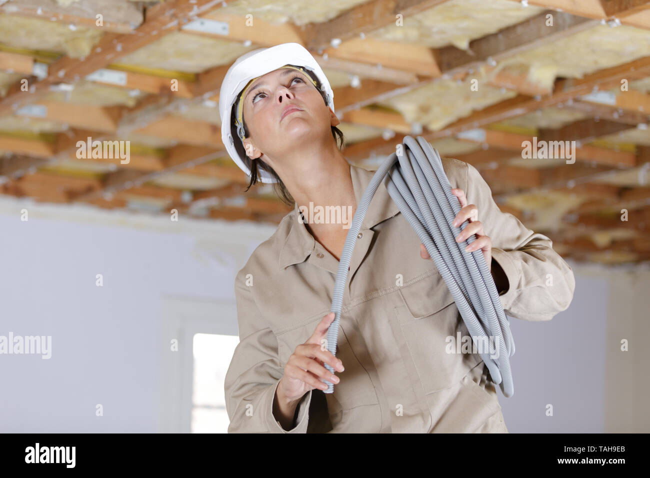 female eleectrician putting pipes in the ceiling Stock Photo