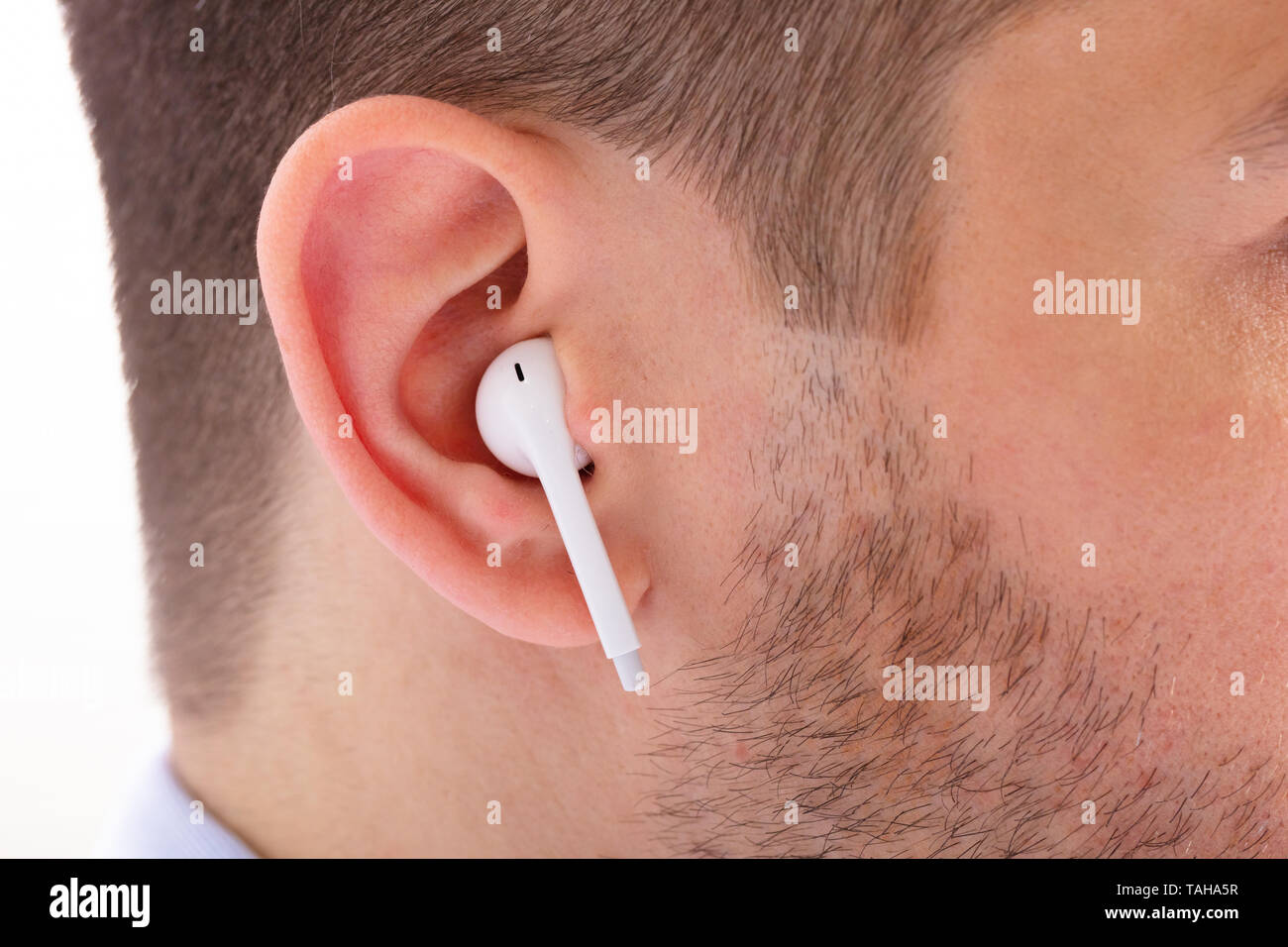 Close-up Of Man Listening To Music Uses Modern Wireless Earphone Stock Photo