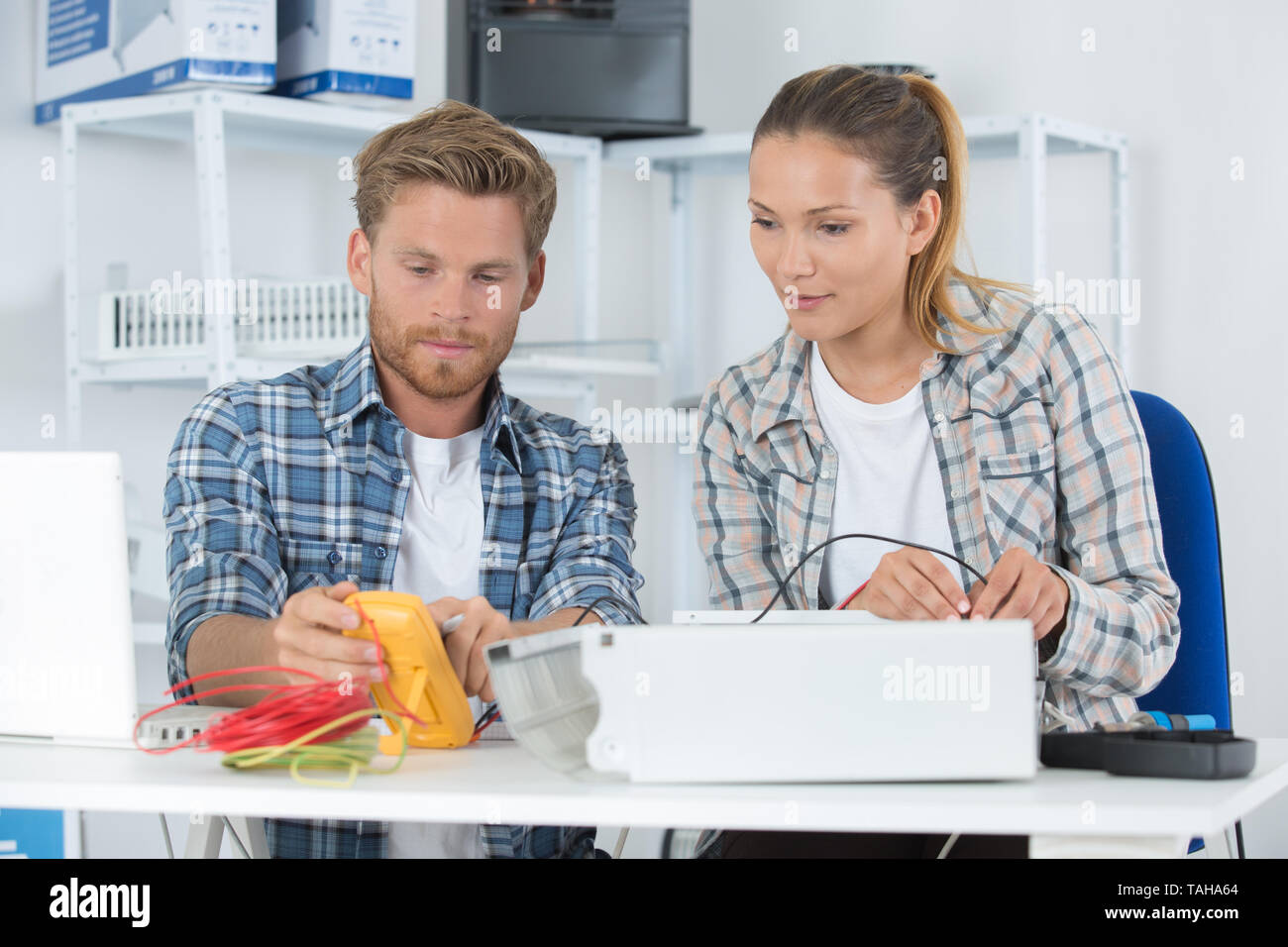 coworkers using multimeter to test electrical appliance Stock Photo