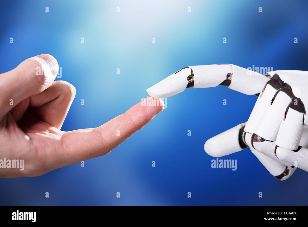 Robot Touching Man's Index Finger Against Digital Backdrop Stock Photo