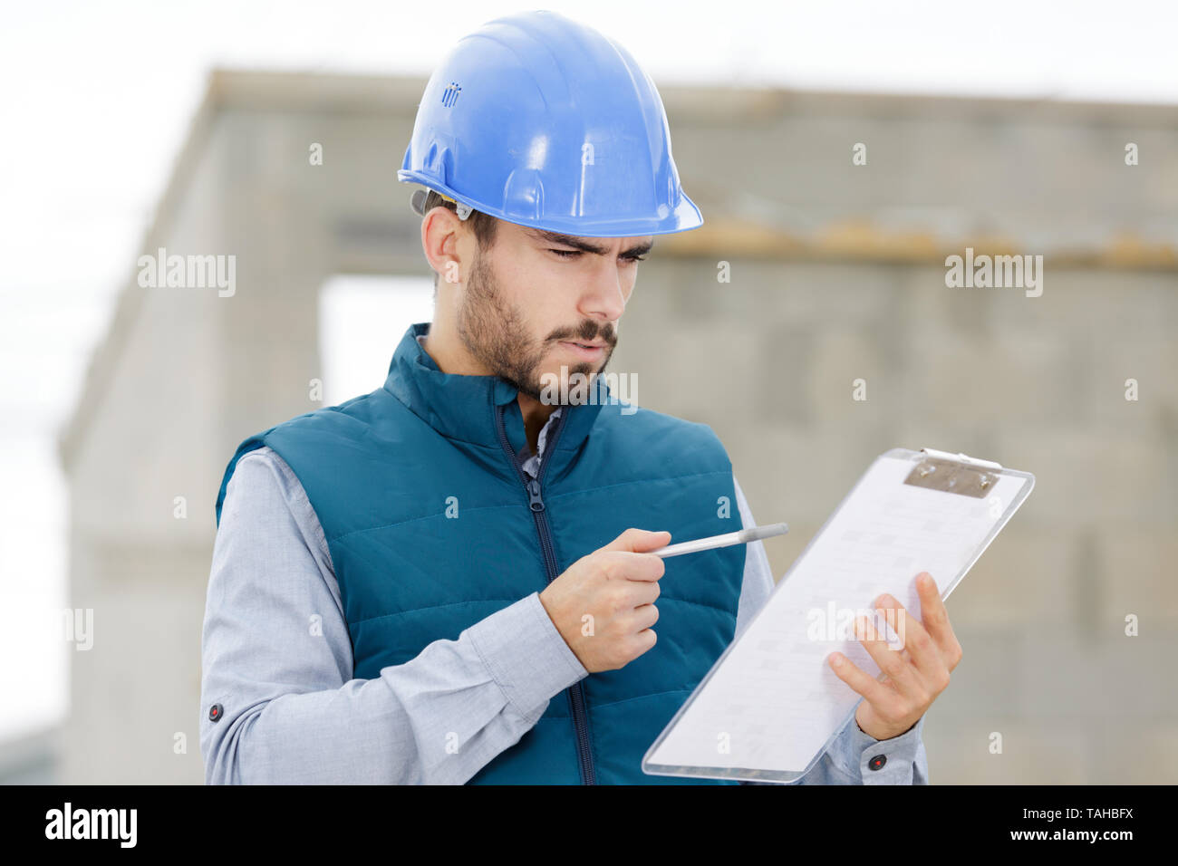 workman in blue dungarees with clipboard Stock Photo