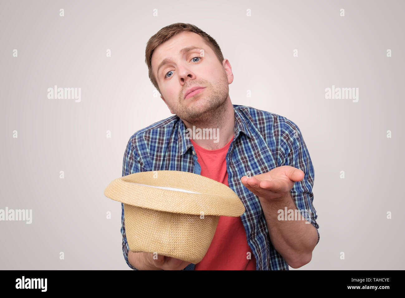 young man holding hat and begging for money Stock Photo Alamy