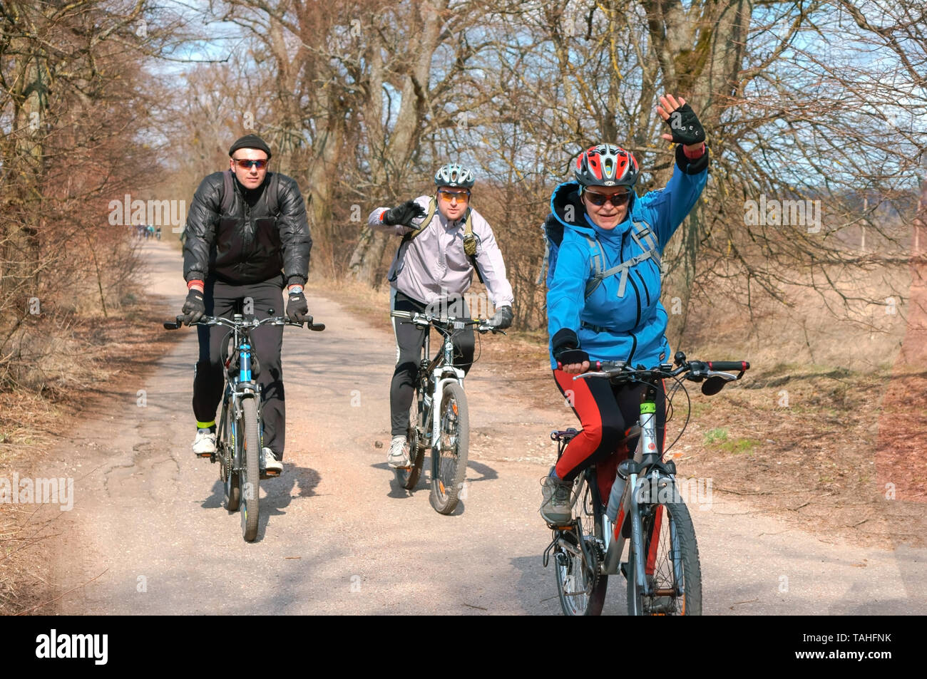 three cyclists outside the city, spring bike ride, Kaliningrad region, Russia, March 31, 2019 Stock Photo