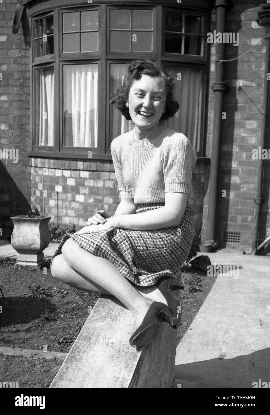 Family Life in the UK c1950  A young woman poses on a wall at the front of a house in a stunning portrait.  Photo by Tony Henshaw Stock Photo