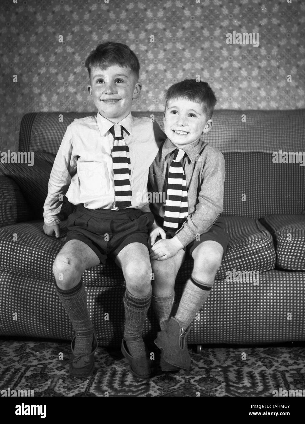 Family Life in the UK c1950  Two smartly dressed young brothers looking happy on a settee  Photo by Tony Henshaw Stock Photo