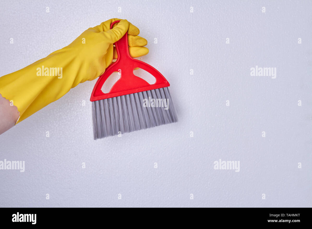 Hand with glove holding cleaning broom. Person in rubber glove holding red cleaning brush. Space for text. Stock Photo