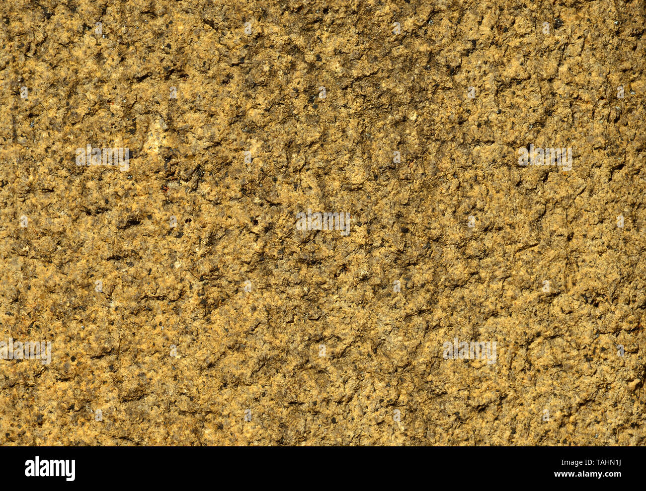 Yellow stone wall with rough surface as background Stock Photo