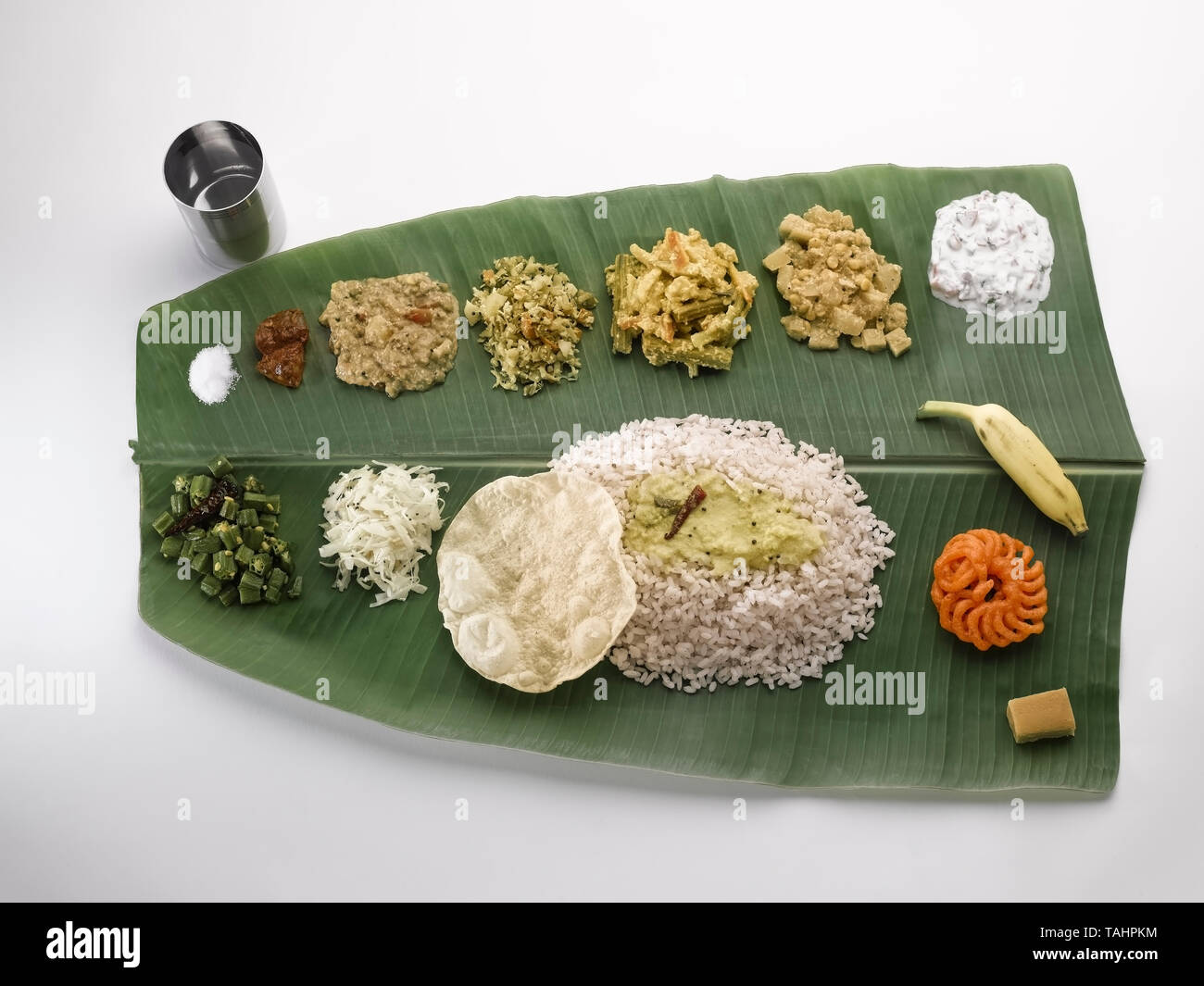 A STILL LIFE OF A TRADITIONAL TAMIL, SOUTH INDIAN ,  LUNCH SERVED ON A GREEN PLANTAIN LEAF. FROM TOP LEFT GOING RIGHT ARE-SALT; MANGO PICKLE; COCUNUT  Stock Photo