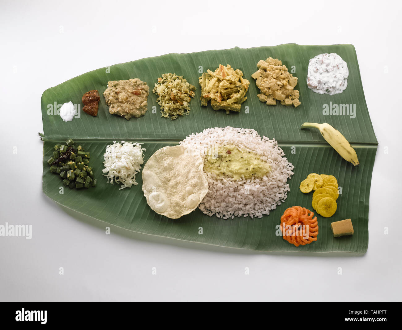 A STILL LIFE OF A TRADITIONAL TAMIL, SOUTH INDIAN ,  LUNCH SERVED ON A GREEN PLANTAIN LEAF. FROM TOP LEFT GOING RIGHT ARE-SALT; MANGO PICKLE; COCUNUT  Stock Photo