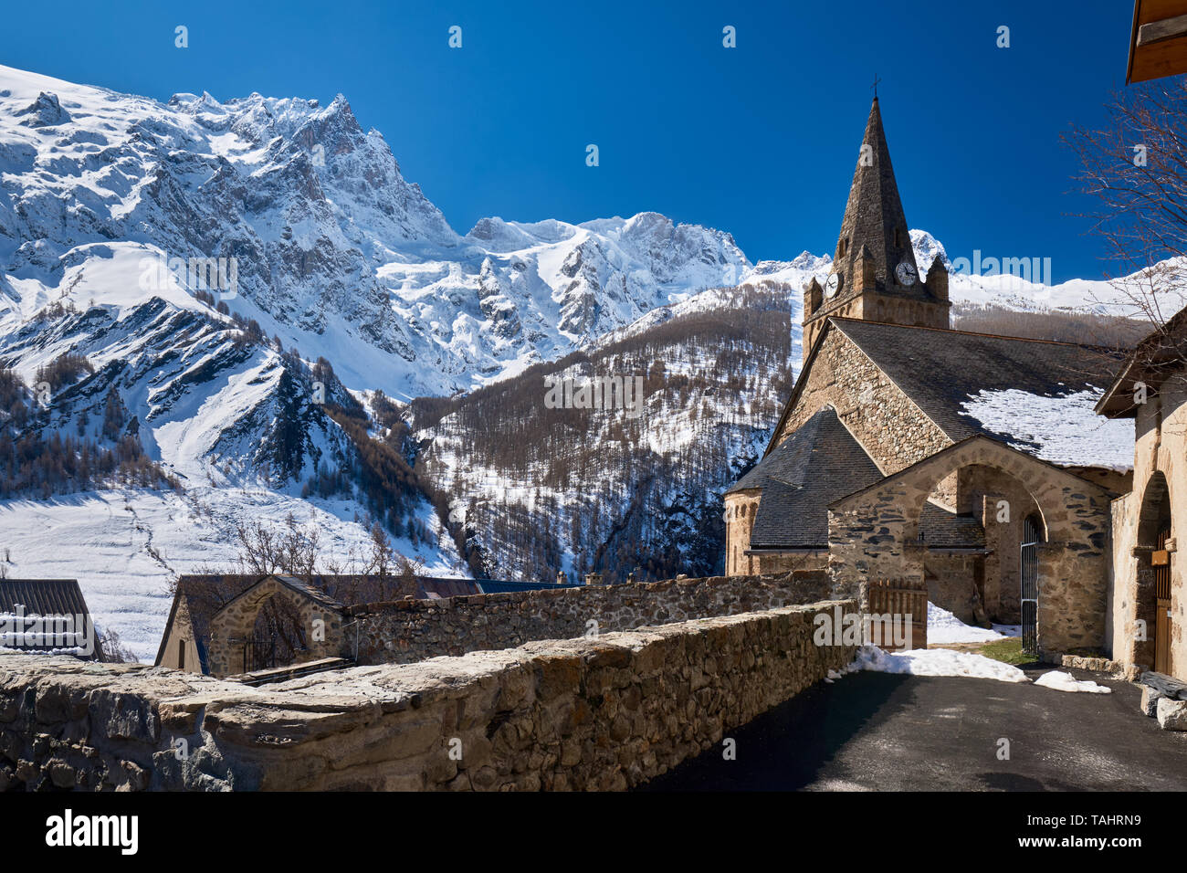 France, Hautes-Alpes (05), La Grave, Ecrins National Park - The church of Notre Dame de l'Assomption de la Grave in winter with view on La Meije Peak Stock Photo