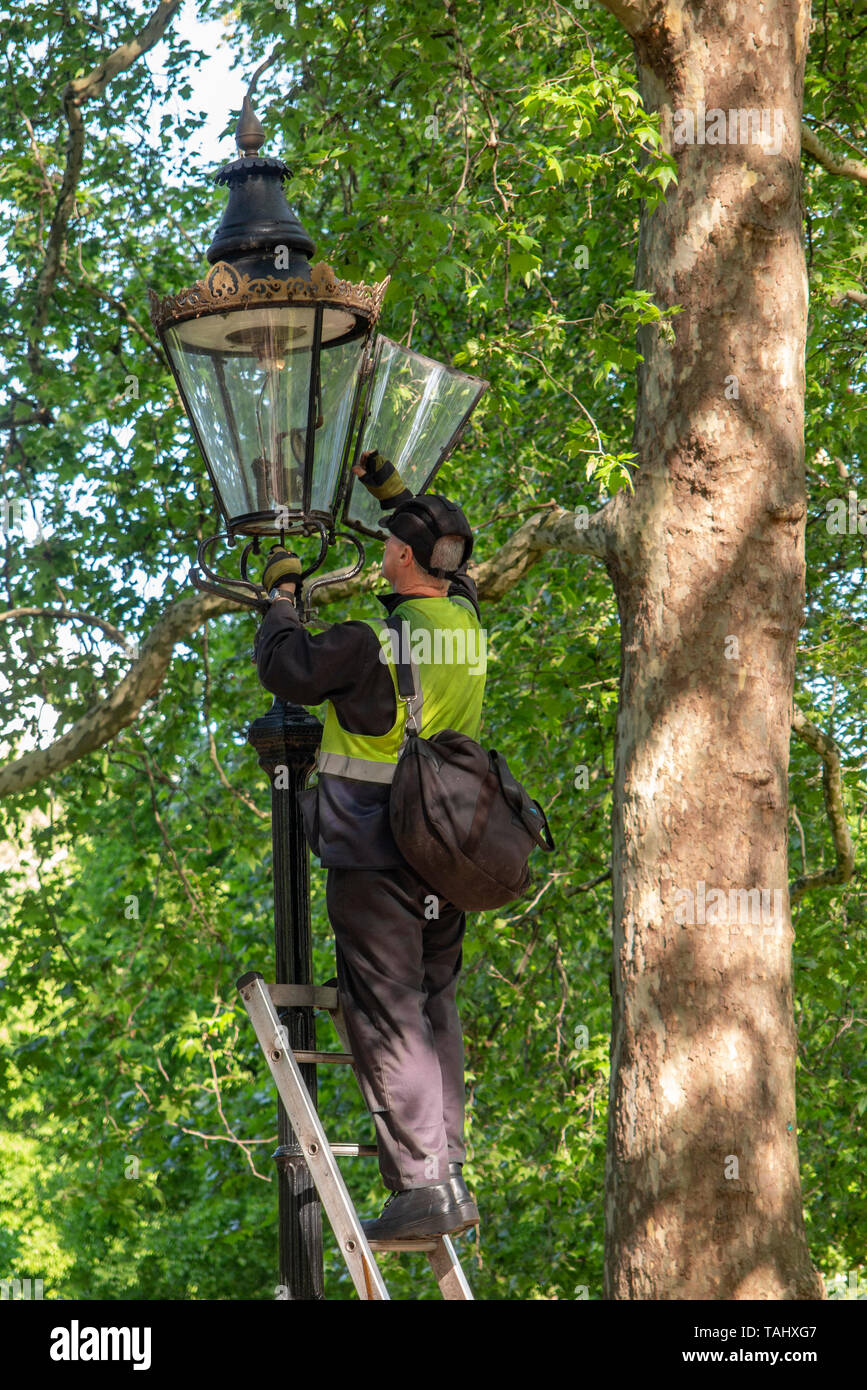 London street light gas lighters turning off the street lights in Green Park on a sunny day in spring Stock Photo