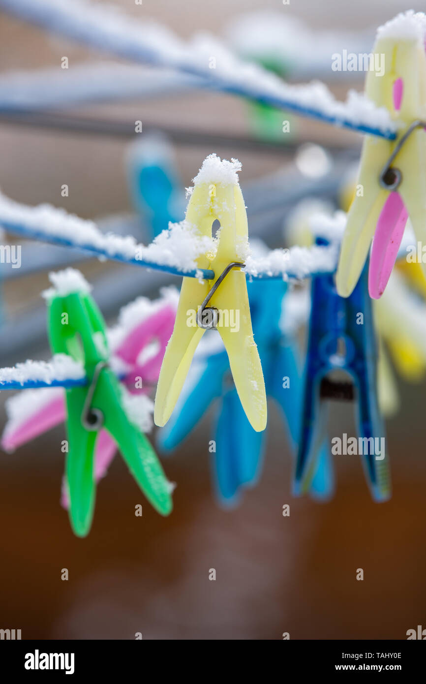 snow covered plastic clothes pegs on rotary washing line Stock Photo