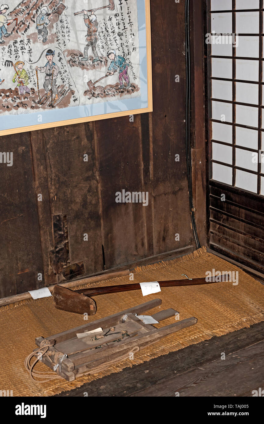 Gardening objects displayed on floor and partial painting on wall of a Gassho-zukuri  house,  Hida Minzoku Mura  folk village and museum, Takayama, Stock Photo