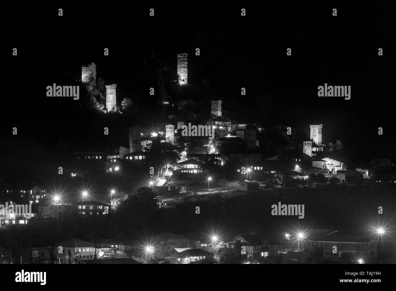 View of Svan towers with night illumination in Mestia village at night. Upper Svaneti, Georgia. Black and white Stock Photo