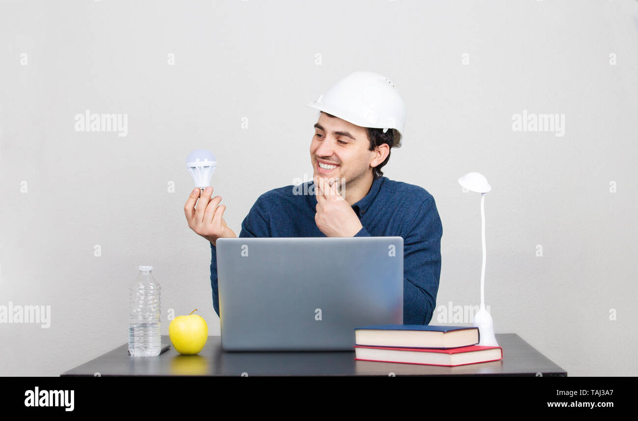 Happy enginer having eco energy saving idea holding modern light bulb .Ecological friendly and sustainable environment.Energy saving concept. Stock Photo