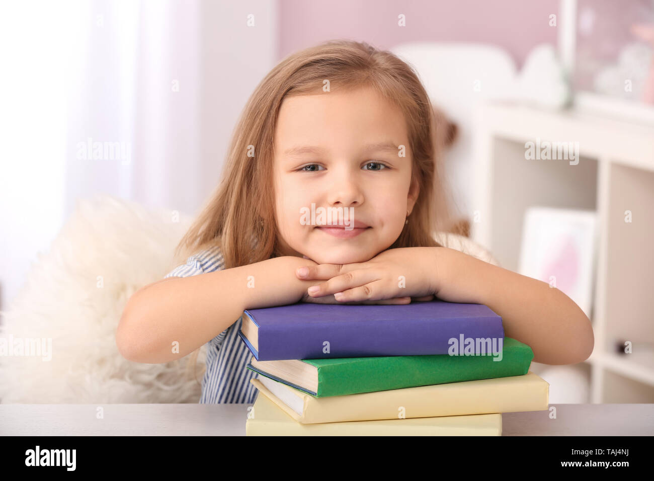 Portrait of cute little girl with books at home Stock Photo - Alamy