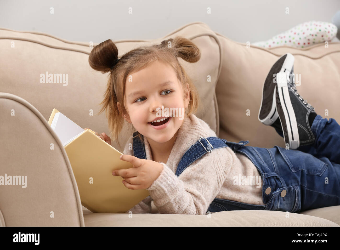 Cute little girl reading book at home Stock Photo - Alamy