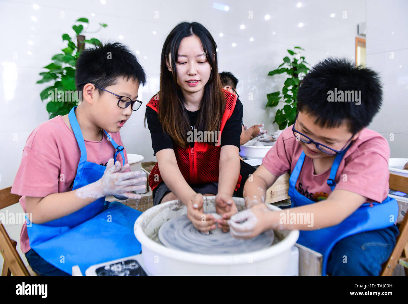 Cixi, China's Zhejiang Province. 25th May, 2019. Pupils make pottery wares under the instruction of a volunteer in Cixi City, east China's Zhejiang Province, May 25, 2019. A volunteer center in Cixi City opened a pottery class for local pupils in celebration of the upcoming International Children's Day. Credit: Xu Yu/Xinhua/Alamy Live News Stock Photo