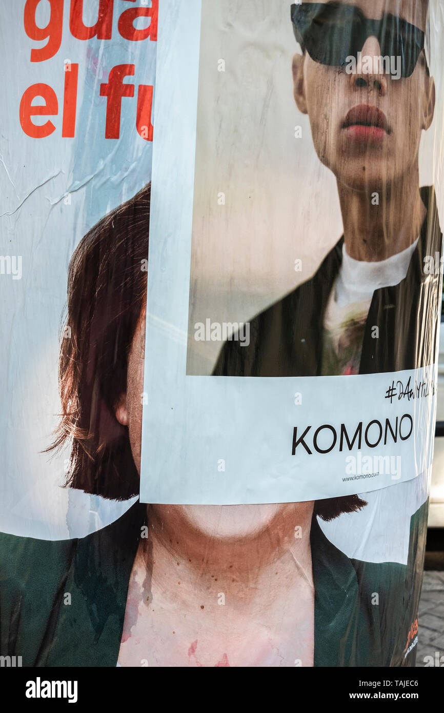 The electoral propaganda poster of the current mayor Ada Colau covered by a commercial poster. Election posters are seen broken, manipulated or covered by other posters during the last week of the election campaign. Stock Photo