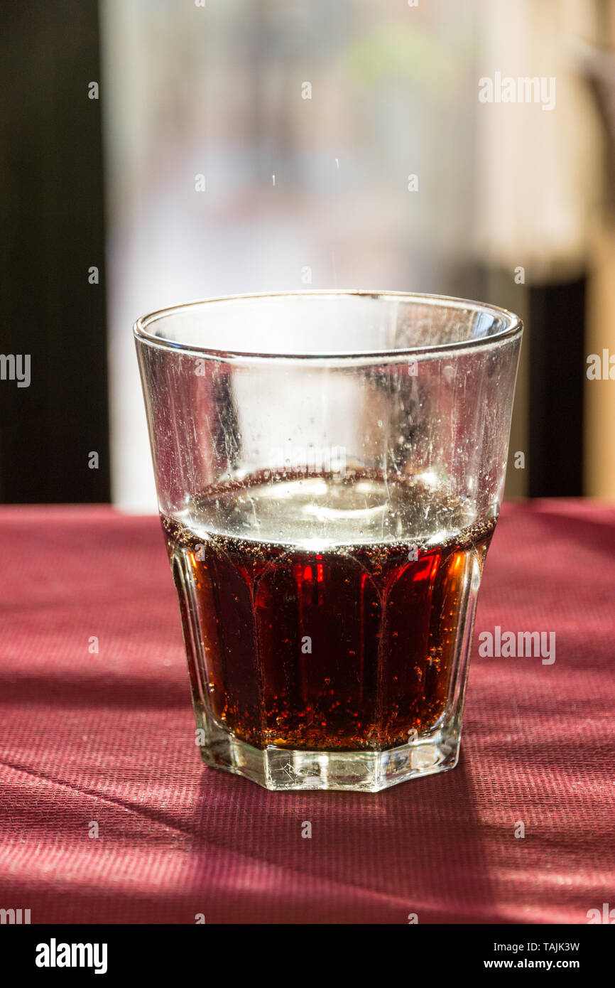 A beautifully backlit glass of red soft drink on a restaurant table in Italy at sunset Stock Photo