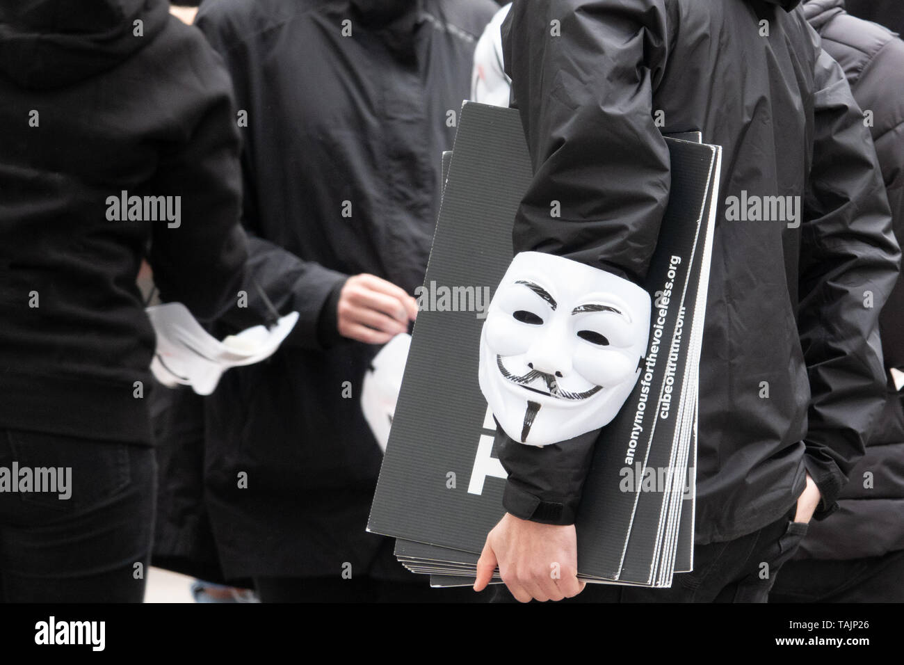 A group of young people dressed all in black goes out on the street to demonstrate with anonymous masks. Stock Photo