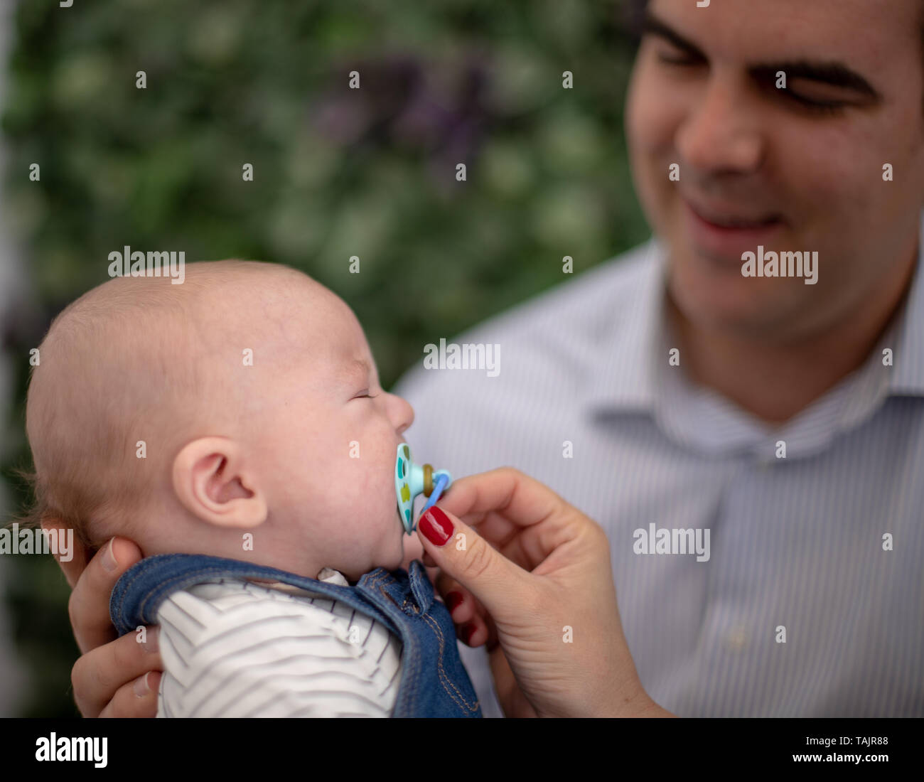 Father tries to put his baby to sleep by keeping him upright and in his