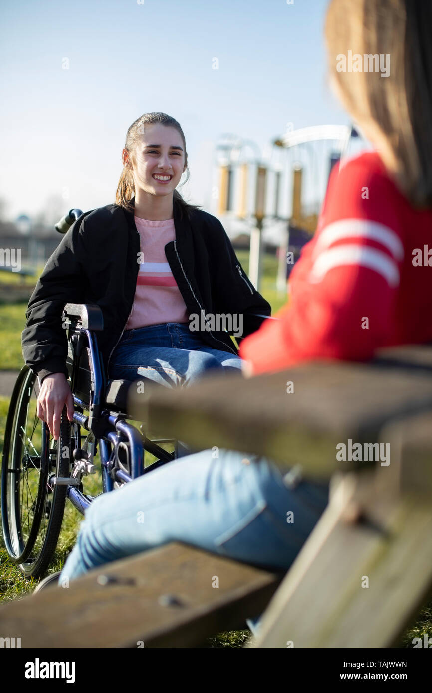 Teenage Girl In Wheelchair Talking With Friend In Park Stock Photo - Alamy