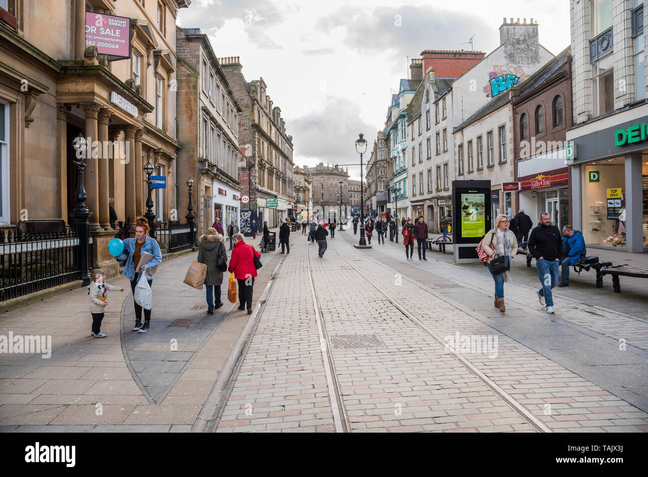 Dundee, UK - March 8, 2018: people strolling along a shopping pedestrian streeton a cloudy winter day Stock Photo