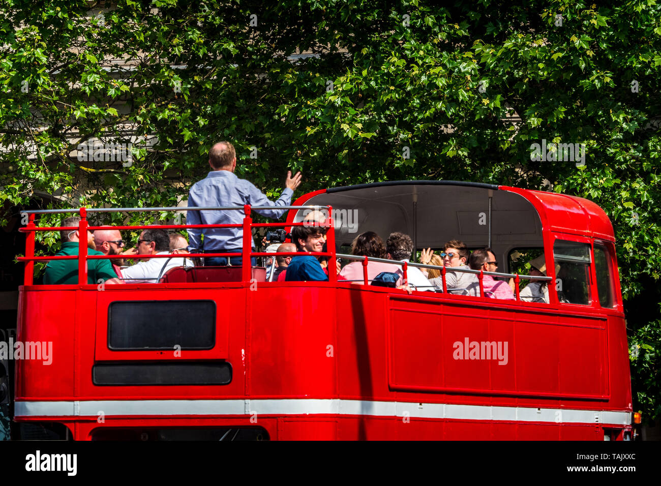 London Tour Bus Guide talks to Tourists on the top deck of a classic  London Routemaster Tour Bus Stock Photo