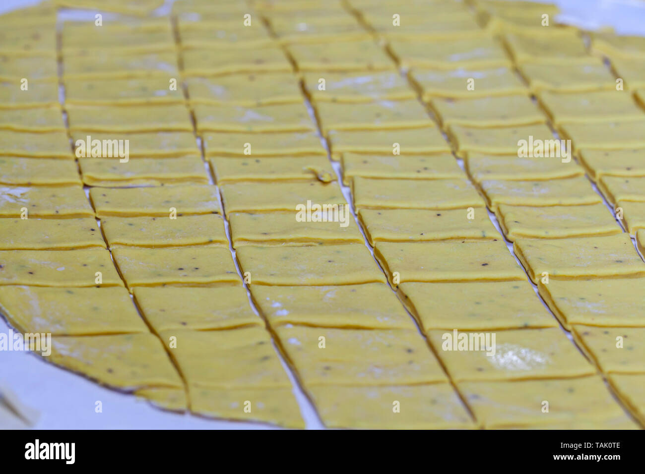 Homemade dumpling dough cut into rectangles on wax paper to be placed in a pot of chicken and chicken broth for chicken and dumplings. Stock Photo